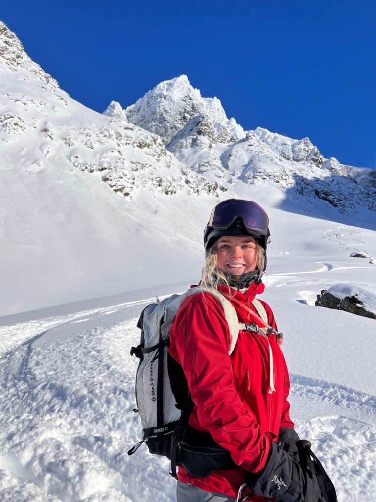 Kvinne er på skitur og smiler mot kamera.