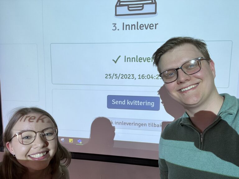 To studenter foran en projektering som sier at de har levert inn oppgaven sin